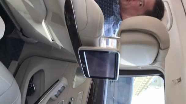 モスクワ, ロシア連邦 - 2018 年 5 月 24 日: 垂直ビデオ。ホワイト本革シートと高級リムジン車の助手席に若い男. — ストック動画
