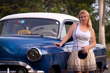 Genç Sarışın kadın mavi eski retro arabanın önüne kalıyor