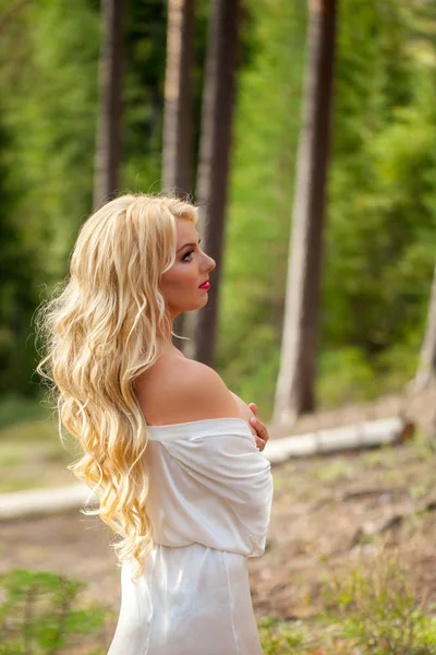 Genç güzel sarışın kadın ormanda poz beyaz pegnoir iç giyim