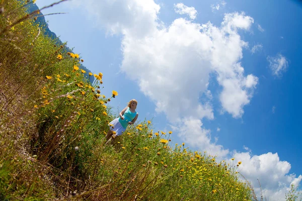 Genç güzel sarışın kız bir papatya alanda onun elinde bir çiçek ile poz standları