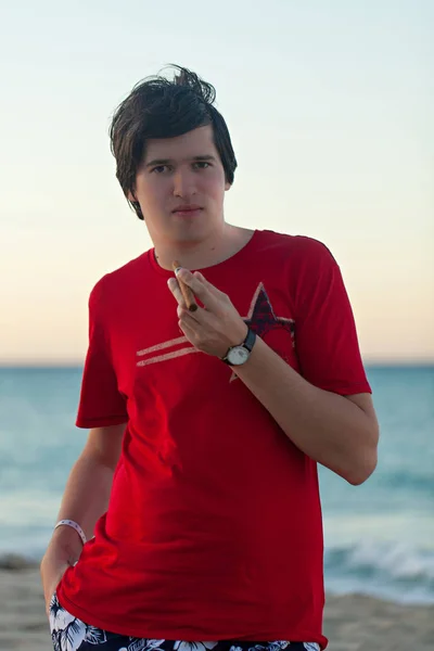 Deniz kenarında kırmızı tişörtlü genç adam