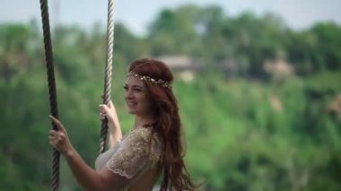 Bir uçuruma Bali bir salıncak üzerinde sallanan bir genç kadın. Kızıl saçlı gelin ona düğün kutlama günü.