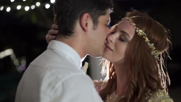 Les mariés s'embrassent dans une villa tropicale la nuit. Lumières sur fond 