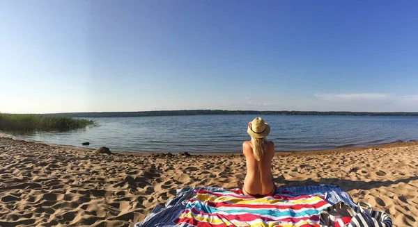 Kumlu plajda üstsüz güneşlenirken genç seksi sarışın kız