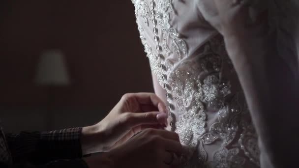 Zapínala nevěsta svatební šaty zblízka. Ruce, upevnění tlačítka na svatební bílé šaty doma — Stock video
