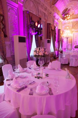 Çatal bıçakla süslenmiş ziyafet masası. Şölen salonunda düğün dekorasyonu. Bayram masası, tabak, peçete, bıçak, çatal. Masa dekorasyonu. Romantik yemek ya da diğer etkinlikler - düğün