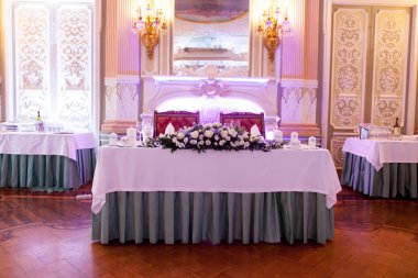 Çatal bıçakla süslenmiş ziyafet masası. Şölen salonunda düğün dekorasyonu. Bayram masası, tabak, peçete, bıçak, çatal. Masa dekorasyonu. Romantik yemek ya da diğer etkinlikler - düğün