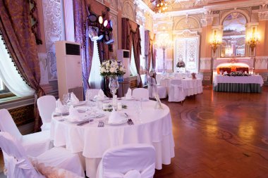 Çatal bıçakla süslenmiş ziyafet masası. Şölen salonunda düğün dekorasyonu. Bayram masası, tabak, peçete, bıçak, çatal. Masa dekorasyonu. Romantik yemek ya da diğer etkinlikler - düğün