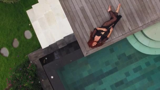 Mujer sexy joven en lencería negra tendida cerca de la piscina en villa de lujo — Vídeos de Stock