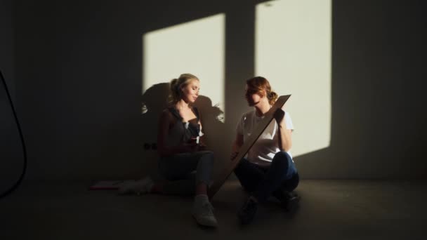 Dos niñas en el sitio de construcción discutiendo y medir el suelo de parquet para su piso — Vídeo de stock