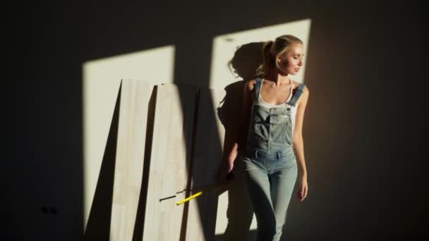 Chica joven trabajadora en el sitio de construcción en su apartamento medir piso laminado — Vídeo de stock