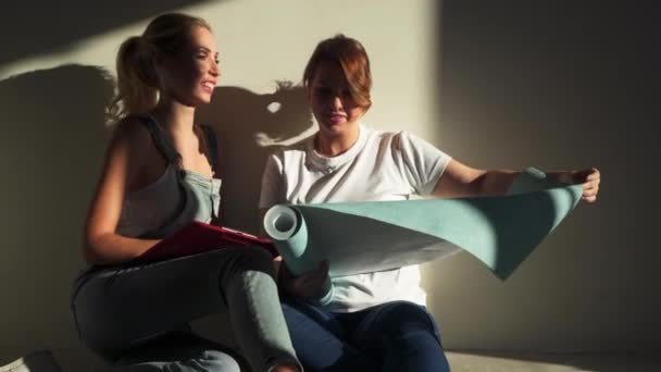 Två flickor på bygg arbets platsen diskuterar och välja tapeter för sin lägenhet — Stockvideo