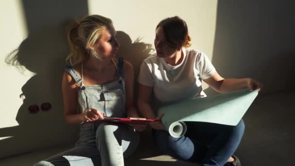 Dwie dziewczyny na budowie dyskusji i wyboru tapety na ich mieszkanie — Wideo stockowe