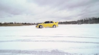 Kış aylarında karla kaplı göl üzerinde buzlu pistte araba sürüş. Kış aylarında kar yarışı pistinde spor araba yarışı. Karlı bir yolda bir yarış arabası sürüş.