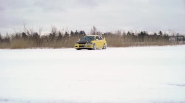 Kış aylarında karla kaplı göl üzerinde buzlu pistte araba sürüş. Kış aylarında kar yarışı pistinde spor araba yarışı. Karlı bir yolda bir yarış arabası sürüş.