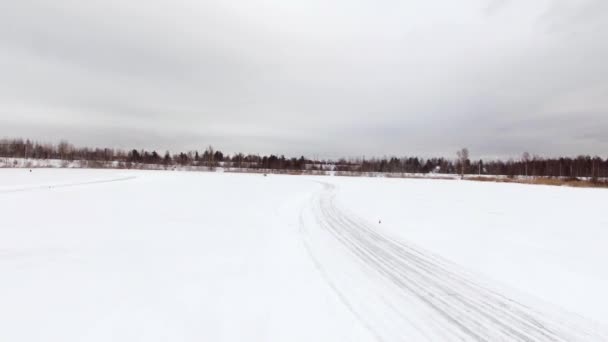 Voiture conduit par piste glacée sur le lac enneigé en hiver. Vue aérienne. Course de voitures de sport sur piste de course de neige en hiver. Conduire une voiture de course sur une route enneigée . — Video