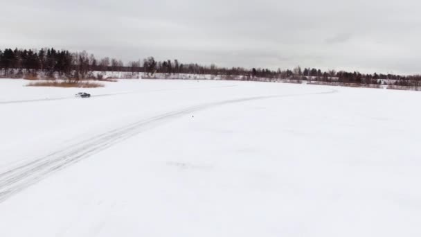 Napęd samochodów przez oblodzonym torze na śniegu objętych jeziora w zimie. Widok z lotu ptaka. Samochód sportowy, wyścigi na torze śniegu w zimie. Prowadzenie samochodu wyścigu na zaśnieżonej drodze. — Wideo stockowe