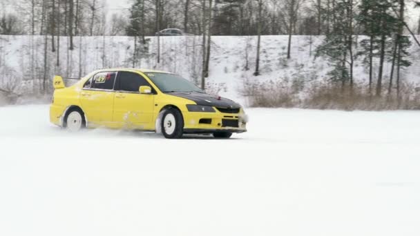 Auto rijdt door ijzige track op sneeuw vallen meer op winter. Sport auto racen op circuit van de sneeuw in de winter. Een raceauto rijden op een besneeuwde weg. — Stockvideo