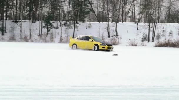Auto rijdt door ijzige track op sneeuw vallen meer op winter. Sport auto racen op circuit van de sneeuw in de winter. Een raceauto rijden op een besneeuwde weg. — Stockvideo
