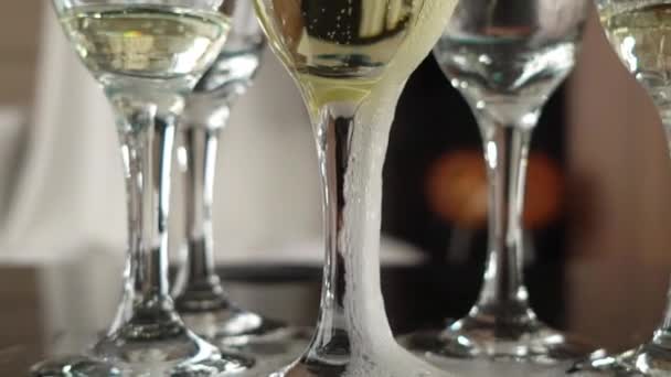 Наливание шампанского из бутылки в пустые бокалы за столом — стоковое видео