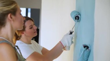 İki kadın işçi silindir daire veya ev duvarlarda boya kullanarak. İnşaat, onarım ve yenileme.