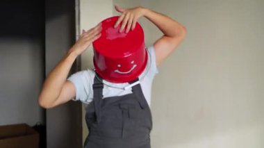 Kafasında kırmızı kova üniformayla işçi var eğlenceli ve dans