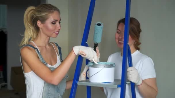 Duas trabalhadoras usando rolo para pintar as paredes do apartamento ou da casa. Construção, reparação e renovação . — Vídeo de Stock