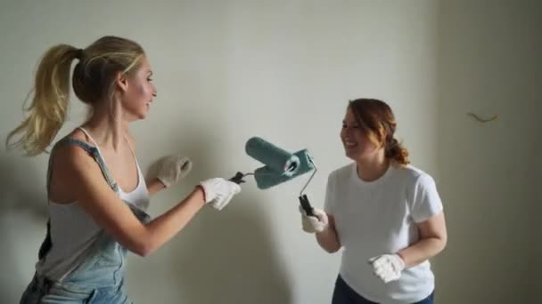 Two woman workers using roller to paint the walls in the apartment or house. Construction, repair and renovation. — Stock Video