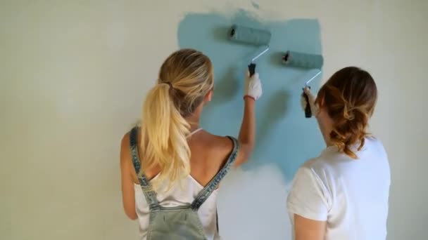 Two woman workers using roller to paint the walls in the apartment or house. Construction, repair and renovation. — Stock Video