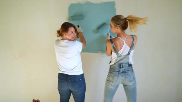 Twee werknemers van de vrouw met de roller om te schilderen van de wanden in het appartement of huis. Bouw, reparatie en renovatie. — Stockvideo