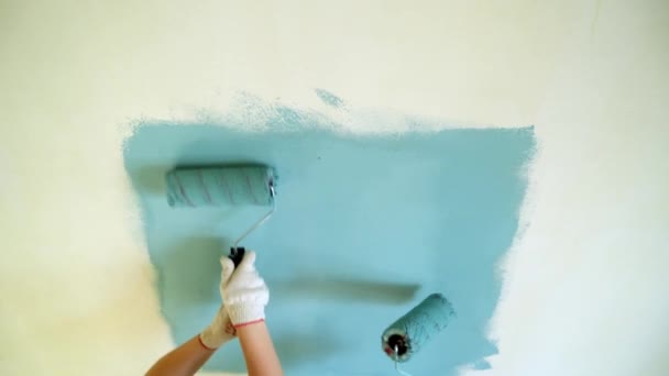 พนักงานหญิงสองคนใช้ลูกกลิ้งทาสีผนังในอพาร์ตเมนต์หรือบ้าน การก่อสร้าง ซ่อมแซม และปรับปรุง . — วีดีโอสต็อก