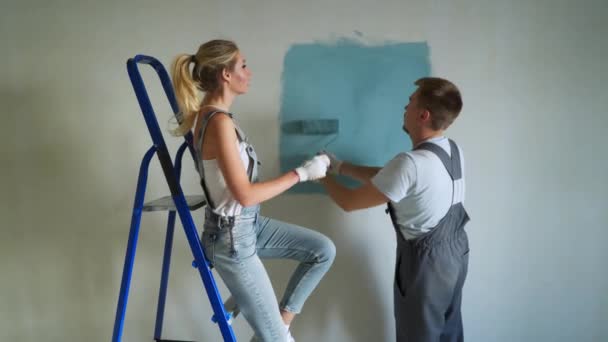 Young family couple worker using roller to paint the walls in the apartment or house. — Stock Video