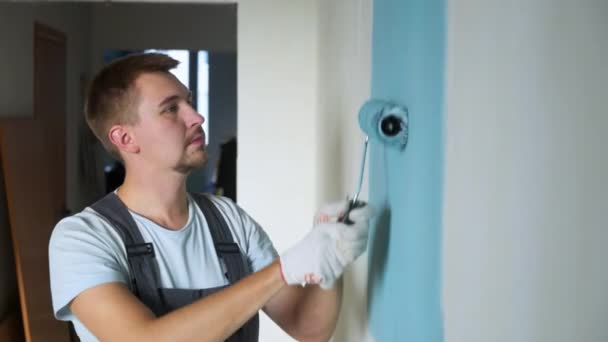 Ungt familiepar som bruker rull til å male veggene i leiligheten eller huset . – stockvideo