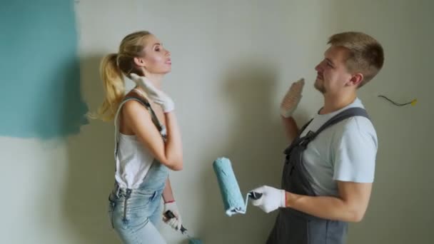 Pareja familiar joven que usa rodillo para pintar las paredes del apartamento o casa . — Vídeo de stock