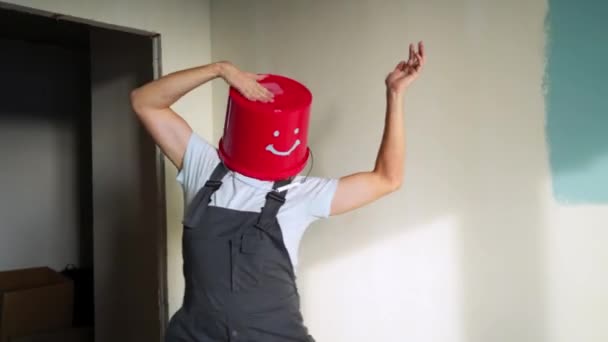 Trabalhador de uniforme com balde vermelho na cabeça se divertir e dançar — Vídeo de Stock