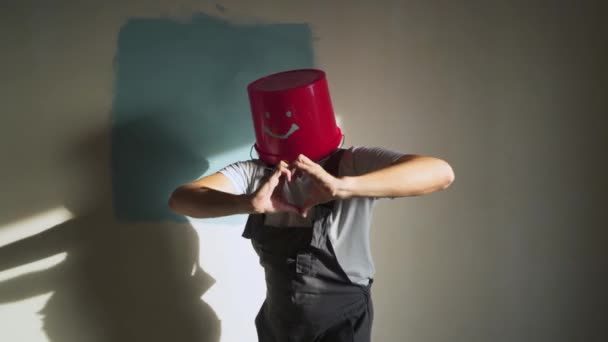 Arbeiter in Uniform mit rotem Eimer auf dem Kopf haben Spaß und tanzen — Stockvideo
