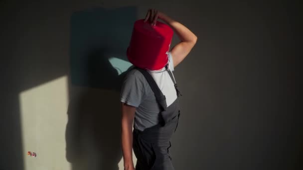 Працівник у формі з червоним відром на голові розважається і танцює — стокове відео