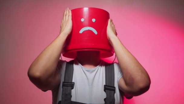 Работник в форме с красным ведром на голове грустный — стоковое видео