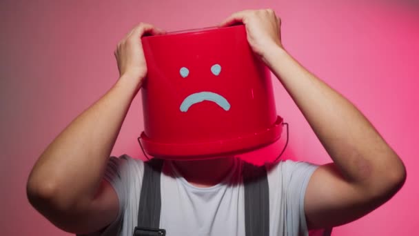 Werknemer in uniform met rode emmer op zijn hoofd triest — Stockvideo