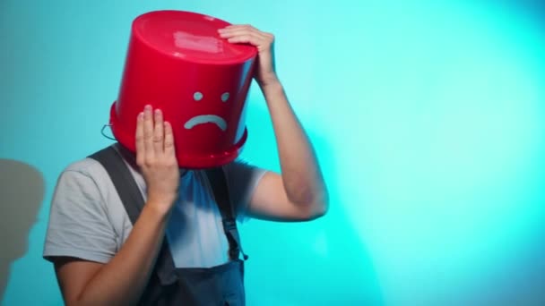 Trabajador en uniforme con cubo rojo en la cabeza triste — Vídeos de Stock