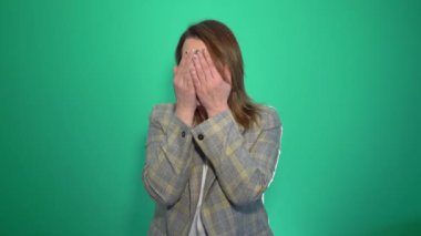 Sarışın genç kadın yakından ağlıyor. Kameraya bakarak ağlayan kadın. Yeşil arka plan üzerinde izole.