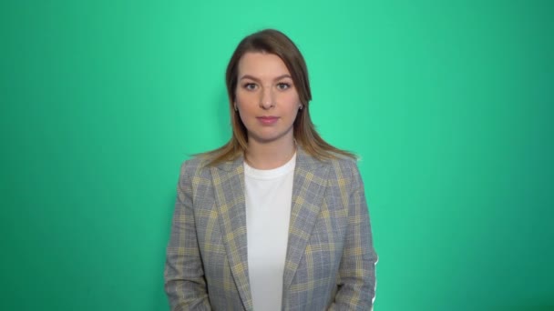 Tystnad, vänligen närbild porträtt av ung kvinna som håller hennes pekfinger på läpparna visar hysch tystnad tecken, stående över grön bakgrund — Stockvideo