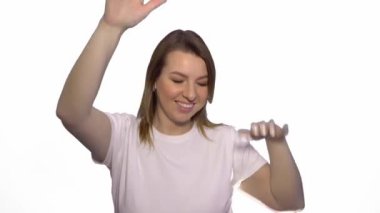 Mutlu kaygısız kadın dans ve beyaz arka plan üzerinde kamera bakıyor