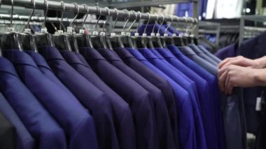 Alışveriş ve moda konsepti-genç adam seçimi ve alışveriş merkezi veya giyim mağazasında ceket çalışıyor
