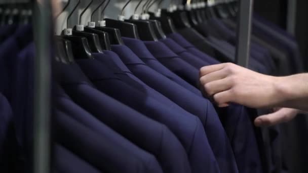 Alışveriş ve moda konsepti-genç adam seçimi ve alışveriş merkezi veya giyim mağazasında ceket çalışıyor — Stok video