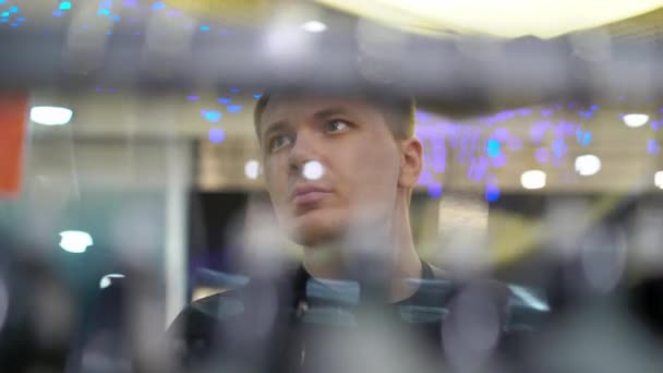 Mladý atraktivní muž, který se dívá na výkladní okno s mentálové komplety v obchoďáku — Stock video
