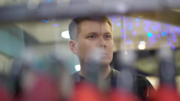 Jovem homem atraente olhando para vitrine com homens ternos no shopping — Vídeo de Stock