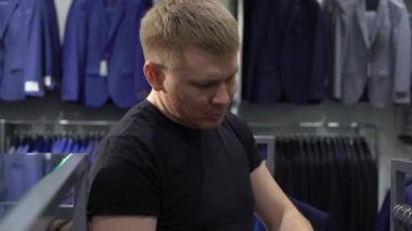 Alışveriş ve moda konsepti-genç adam seçimi ve alışveriş merkezi veya giyim mağazasında ceket çalışıyor