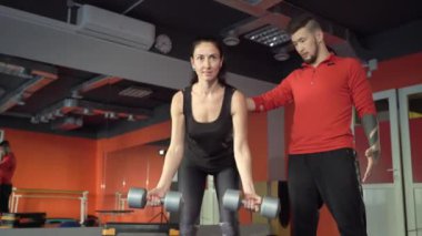 Genç sağlıklı sportif aktif şekil kız ile bir yakışıklı yararlı kişisel eğitmen yanında onu içinde the spor salonu.
