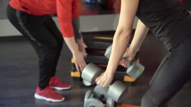 Genç sağlıklı sportif aktif şekil kız ile bir yakışıklı yararlı kişisel eğitmen yanında onu içinde the spor salonu.